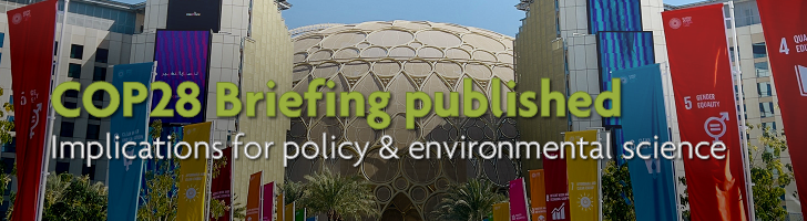 Expo City Dubai with sustainable development goals on banners and overlaid text "COP28 Briefing published: implications for policy and environmental science"