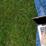 Student sitting on grass working on laptop