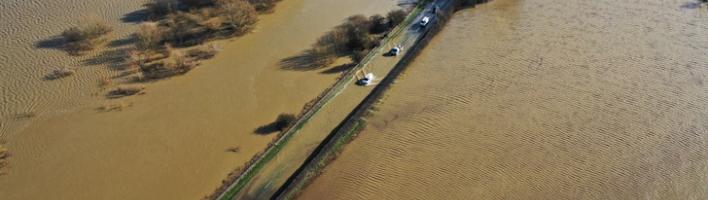 Photograph of flooded road and flooded fields in the UK taken from above 