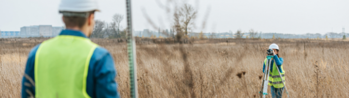 Environmental professionals working in a pair in a field with technical instruments