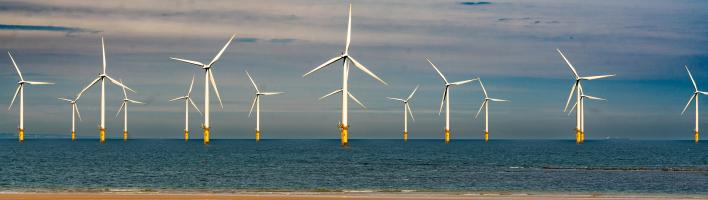 Offshore wind turbines with a sandy beach in the foreground