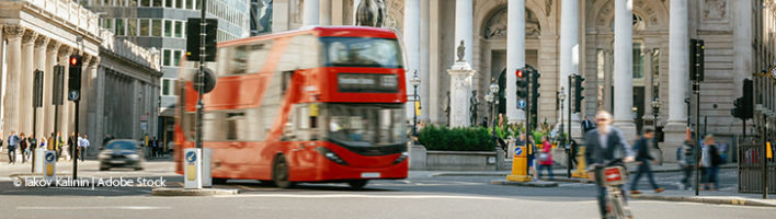 A red London bus drives past the London Exchange