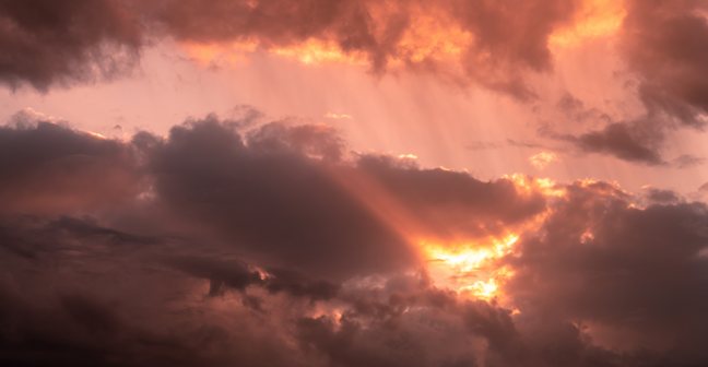 Photograph of clouds with orange light breaking through