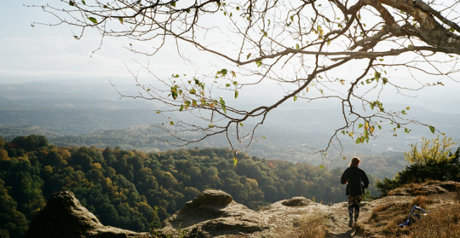 woman standing at the end of a path admiring a view of mountains