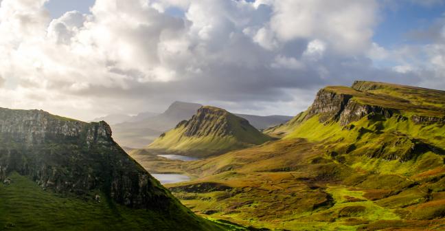 A dramatic landscape in the UK, with rolling green mountain scenery and a cloudy but blue sky. Copyright Dominic Meijers, Adobe Stock