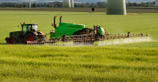 Tractor in a field with wind turbines in the background