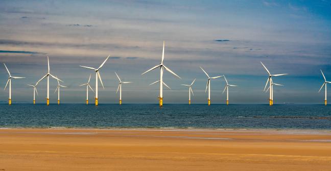Offshore wind turbines with a sandy beach in the foreground