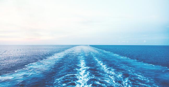 View of blue sea with water ripples from a moving boat not shown.