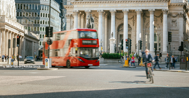 A red London bus drives past the London Exchange