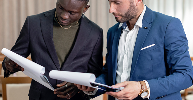 Two people in suits looking at charts