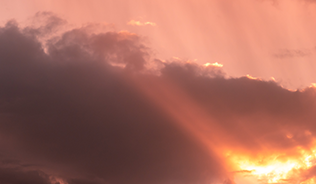Photograph of clouds with orange light breaking through