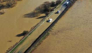 Photograph of flooded road and flooded fields in the UK taken from above 