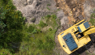 Yellow digger clearing land from above
