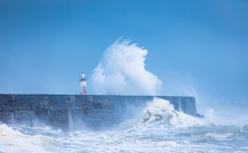 A wave crashes against a see wall