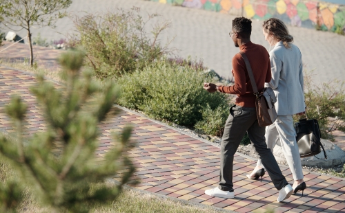 Colleagues walk and talk outdoors