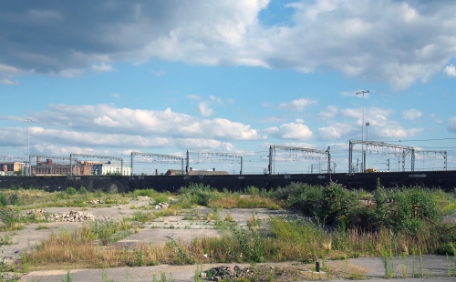 Unused urban brownfield site with open land covered in cracked overgrown concrete