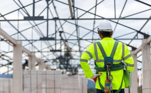 Construction worker in hi-vis looking at scaffolded project