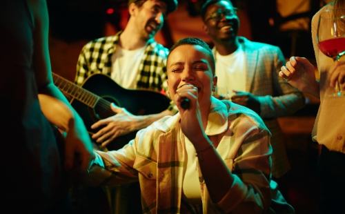 Young black woman sings while being with her friends on night party in bar.
