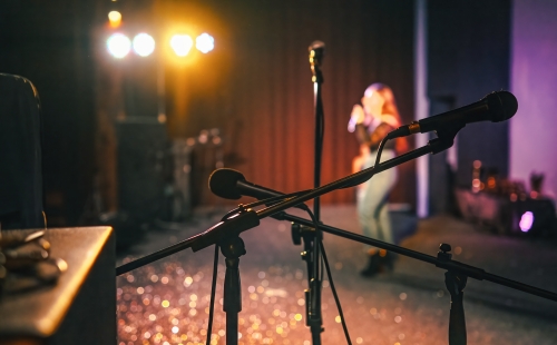 Stage with microphones and person singing in background