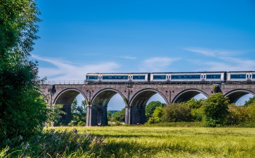 Train going over viaduct in countryside