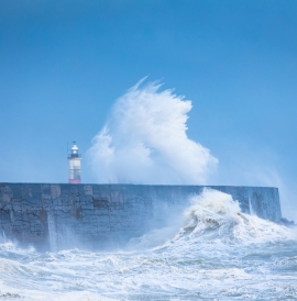 A wave crashes against a see wall
