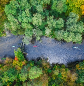 Group of kayakers paddling down a river, aerial view