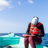 Marine biologist writing down data sitting on a boat, out to sea